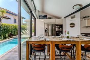a dining room with a table and chairs and a swimming pool at La Villa Sanson in Arcachon