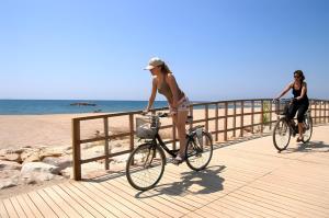 two women riding bikes on a boardwalk at the beach at Villa María Magdalena in Cambrils