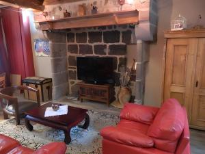 a living room with a red couch and a fireplace at La Maison De Marie in Murat