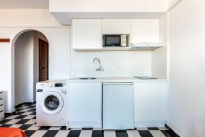 a white kitchen with a washing machine and a microwave at Estudio Mirada 304 in Es Pujols