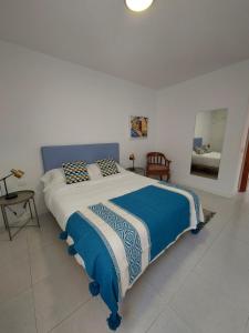 a bedroom with a large bed with a blue and white blanket at Casa Guayo in Tías +30 photos