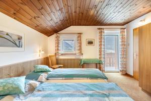 two beds in a room with wooden ceilings and windows at Unterhauserhof App C in Valdaora