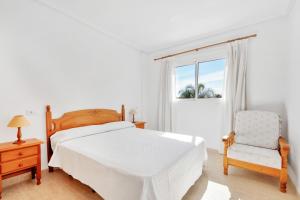 a bedroom with a bed and a chair and a window at Casa en playa con piscina Novamar in Santa Pola +16 photos