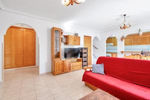 a living room with a red couch and a kitchen at Casa en playa con piscina Novamar in Santa Pola