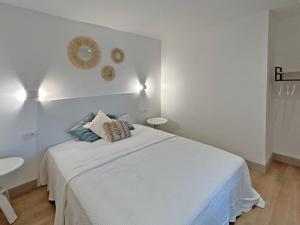 a white bedroom with a bed and a mirror on the wall at Au p'tit Colombier in Hillion