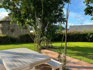 a white bench in a yard with a tree at Au p'tit Colombier in Hillion