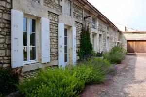 a brick building with white windows and plants on it at Gite La Saintonge in Sainte-Gemme +16 photos