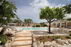 a pool with two benches and a tree in a yard at La Dimora dello Zio, with pool in Ostuni