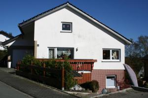 a white house with a fence in front of it at Ferienwohnung Sammet in Brilon