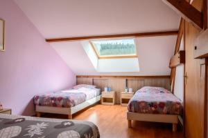 a attic room with two beds and a window at Gîte La Ramée in Ban-sur-Meurthe-Clefcy