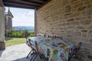 a table and chairs on a patio with a stone wall at Casa De Marica in A Estrada