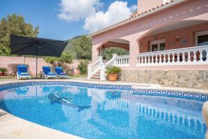 a house with a swimming pool with two chairs and an umbrella at Villa Epi in Cala Ratjada
