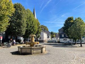 a fountain in the middle of a courtyard with a church at Gemütliche Ferienwohnung in Drolshagen