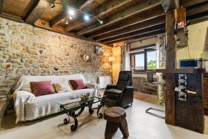 a living room with a couch and a stone wall at Casa Rural Adrimar in Selorio