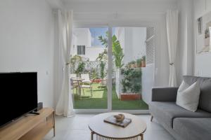 a living room with a couch and a tv at La Casa de Emilie- Solo Familias in Conil de la Frontera
