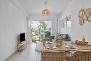 a dining room and living room with a table and chairs at La Casa de Emilie- Solo Familias in Conil de la Frontera