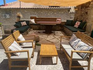 a patio with chairs and a table and a bench at Traditional Stone House in Lazaráta