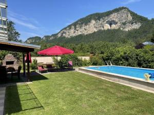 a backyard with a swimming pool and a red umbrella at Haus Linsendorf in Gallizien +12 photos