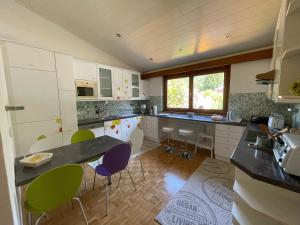 a kitchen with white cabinets and green chairs at Haus Linsendorf in Gallizien