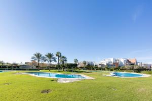 a couple of pools in a park with palm trees at Apartamento Luz De Baria in Vera