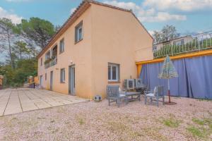 a house with two chairs and a table and an umbrella at Charmant appartement avec terrasse in Brignoles