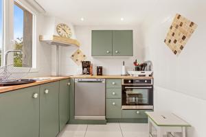 a kitchen with green cabinets and a clock on the wall at Charmant appartement avec terrasse in Brignoles
