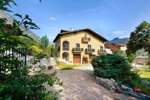 a large yellow house with a brick driveway at Maison Lorent in Champdepraz