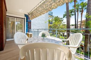 a white table and chairs on a balcony with palm trees at beach and pool in Cambrils