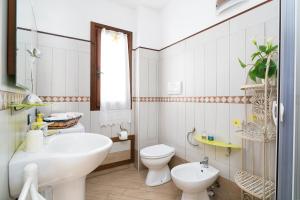 a white bathroom with a sink and a toilet at Al mare da Pépé in Budoni