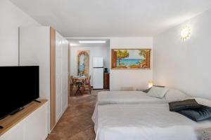 a bedroom with two beds and a flat screen tv at Il Giardino del Sole, Chalet Salvia in Garlenda
