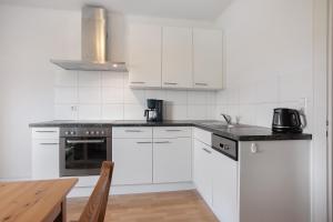 a kitchen with white cabinets and a wooden table at Haus Zapf in Kressbronn am Bodensee