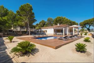 a house with a swimming pool and lounge chairs at Anglesos in Can Picafort