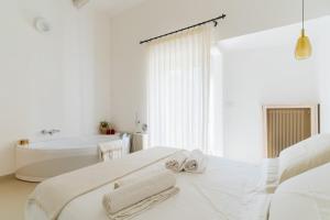 a white bathroom with a tub and a bed with towels at Bacchus Historic Home in Otranto