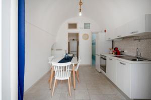a kitchen with white cabinets and a table and chairs at Tritone 30 in Polignano a Mare +13 photos