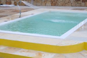 a large swimming pool with a yellow and white curb at Refúgio Paraíso in Santo Amaro +4 photos