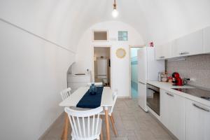 a white kitchen with a table and white chairs at Tritone 30 in Polignano a Mare