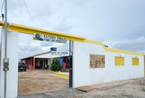 a white building with a yellow roof and a parking lot at Refúgio Paraíso in Santo Amaro