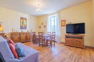 a living room with a tv and a table with chairs at Gîte Le Chant Des Oiseaux in Pradons