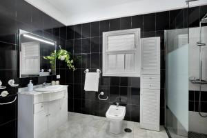 a black tiled bathroom with a toilet and a sink at Los Morales in Arico