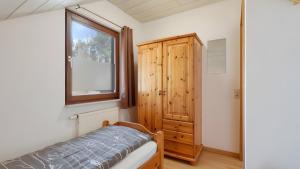 a bedroom with a bed and a window and a wooden cabinet at Waldblick - Stilvolles Ferienhaus in Kemmerode