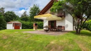 a patio with a table and a yellow umbrella at Waldblick - Stilvolles Ferienhaus in Kemmerode