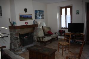a living room with a fireplace and a tv at Maison La Picade in Saint-Mamet