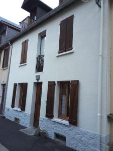 a white building with brown doors and windows at Maison La Picade in Saint-Mamet