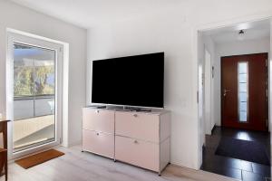 a living room with a flat screen tv on a dresser at Apartment Dreiländer Blick in Wintersweiler