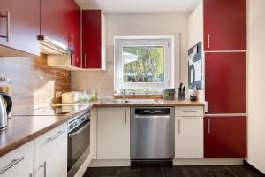 a kitchen with red cabinets and a sink and a window at Apartment Dreiländer Blick in Wintersweiler
