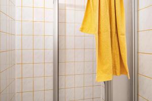 a shower with a yellow towel hanging from a curtain at Möve Aba Appartment 11 in Rerik +23 photos