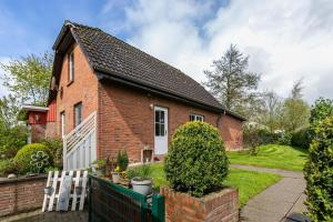 a red brick house with a fence and a yard at De Lüüte Kaat in Offenbüttel