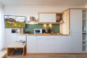 a kitchen with white cabinets and a microwave at Mountain View Corones in Reischach +16 photos