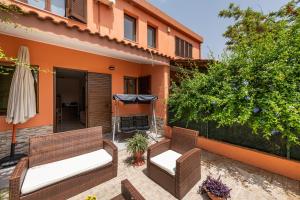 a patio with two wicker chairs and an umbrella at Tara house in Pula