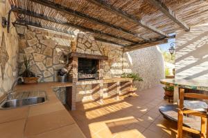an outdoor kitchen with a stone fireplace and a sink at Fuente luz cottage in Frigiliana
